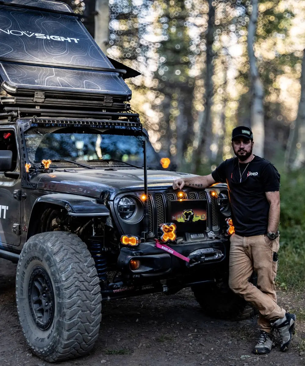 Person leaning against a black off-road vehicle with 'Novsight' branding in a forest setting.